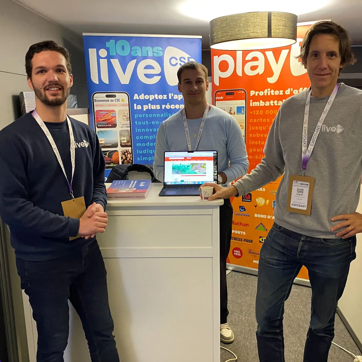 Trois membres de l'équipe devant les kakémonos LiveCSE et Playz d'un salon
